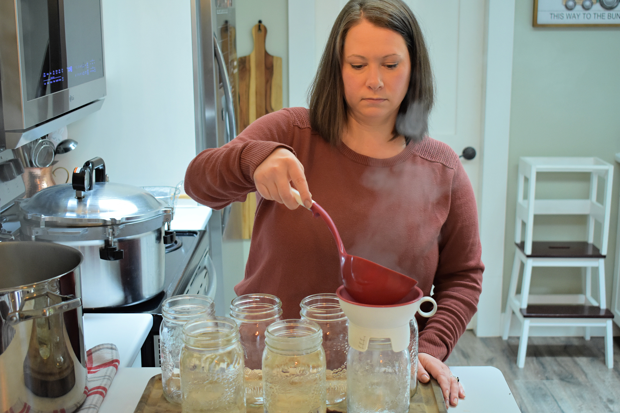 Ladling water into Mason jars for canning.