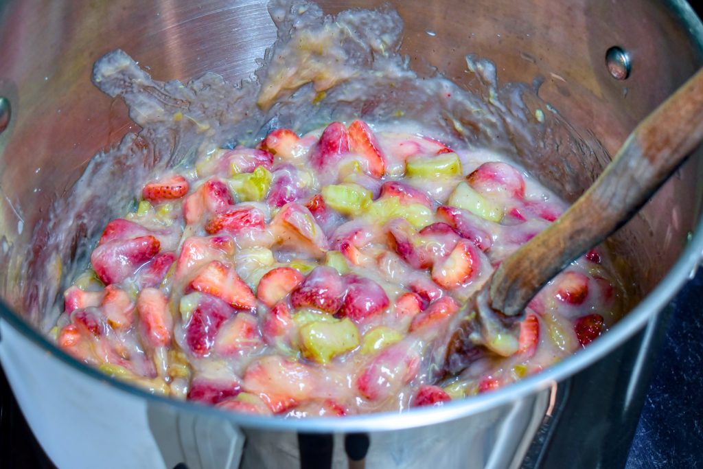 Rhubarb, strawberries and clear jel mixture cooking in a large pot on the stove